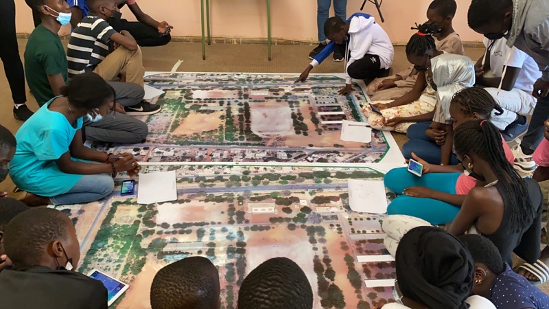 Young participants brainstorming for their block coding exercise with a large-scale map in Dakar, Senegal.