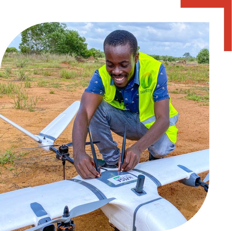 Smiling man adjusting the antenna of an airplain shaped drone outside in a field.